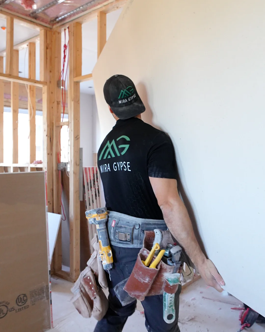 Installateur Mira Gypse transportant une feuille de gypse sur un chantier